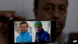 Karrar Haidri, sekretaris Alpine Club Pakistan menunjukkan foto dua pendaki Eropa yang hilang, Tom Ballard dari Inggris (kanan) dan Daniele Nardi dari Italia, di Islamabad, Pakistan, Senin, 4 Maret 2019.