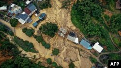 In this aerial view, a car drives past a landslide site after storms in Longyan, in eastern China's Fujian province, on June 17, 2024. (CNS via AFP)