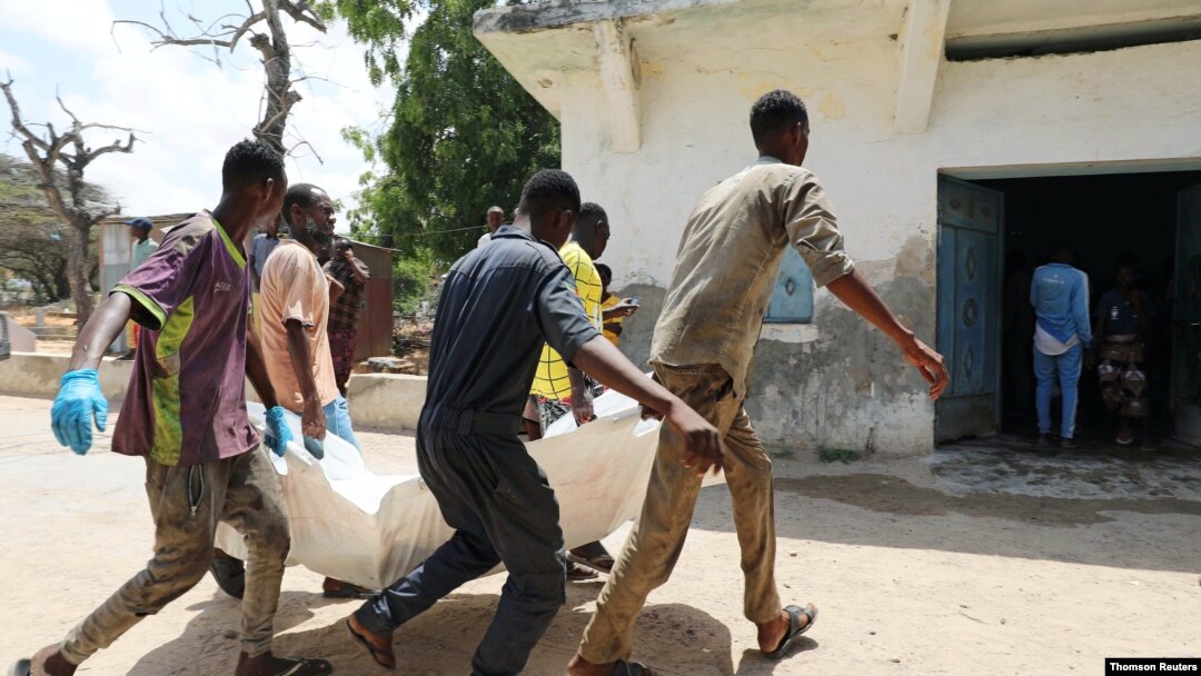 Relatives carry the dead body of a civilian killed in an explosion outside a hotel near the international airport in Mogadishu, July 22, 2019.
