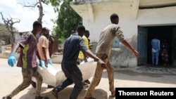 Relatives carry the dead body of a civilian killed in an explosion outside a hotel near the international airport in Mogadishu, July 22, 2019.