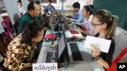 Locals, left, sit for registering their names during a voter registration process of the National Election Committee (NEC) in Phnom Penh, Cambodia, Thursday, Sept. 1, 2016. NEC started its three-month-long voter registration in the day for the next general election scheduled for July 2018. (AP Photo/Heng Sinith)