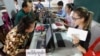 Locals, left, sit for registering their names during a voter registration process of the National Election Committee (NEC) in Phnom Penh, Cambodia, Thursday, Sept. 1, 2016. NEC started its three-month-long voter registration in the day for the next general election scheduled for July 2018. (AP Photo/Heng Sinith)