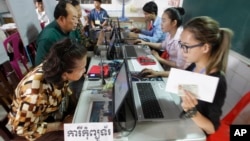 Locals, left, sit for registering their names during a voter registration process of the National Election Committee (NEC) in Phnom Penh, Cambodia, Thursday, Sept. 1, 2016. NEC started its three-month-long voter registration in the day for the next general election scheduled for July 2018. (AP Photo/Heng Sinith)