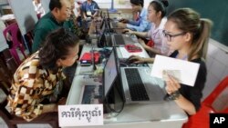 Locals, left, sit for registering their names during a voter registration process of the National Election Committee (NEC) in Phnom Penh, Cambodia, Thursday, Sept. 1, 2016. NEC started its three-month-long voter registration in the day for the next general election scheduled for July 2018. (AP Photo/Heng Sinith)