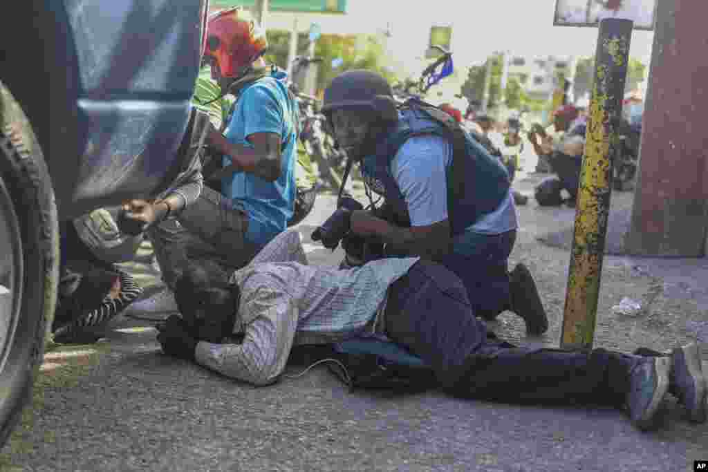 Periodistas se protegen en medio de un tiroteo entre pandillas y policías en Puerto Príncipe, capital de Haití, el lunes 11 de noviembre.