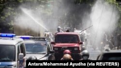 Petugas Satgas COVID-19 mengenakan alat pelindung diri (APD) menyemprotkan disinfektan di jalan untuk mencegah penyebaran COVID-19 di Solo, Jawa Tengah, 6 Juli 2021. (Foto: Antara/Mohammad Ayudha via Reuters)