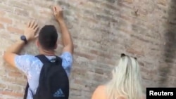 Seorang wisatawan pria memegang kunci tampak mengukir nama di dinding Colosseum di Roma, Italia pada 23 Juni 2023 dalam gambar ini diperoleh dari media sosial.