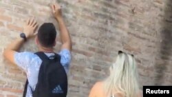 Турист с ключами в руках вырезает надпись на стене Колизея в Риме, Италия, 23 июня 2023 года