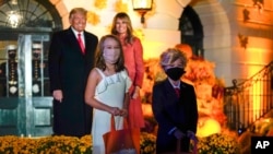 President Donald Trump and first lady Melania Trump poses for a photo with children dressed as them as they greet trick-or-treaters on the South Lawn during a Halloween celebration at the White House, Oct. 25, 2020. 