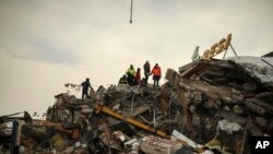 Tim SAR terus melakukan pencarian korban di antara puing-puing bangunan yang runtuh di tengah suhu membeku di Malatya, Turki, Selasa, 7 Februari 2023. (AP/Emrah Gurel)