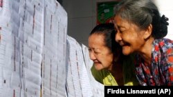 Perempuan lanjut usia mengecek daftar nama caleg di TPS di Bali, Rabu 9 April 2014. (Foto: AP/Firdia Lisnawati)