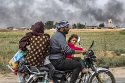 FILE - Members of a Syrian family use a motorcycle to flee the countryside of the northeastern Syrian town of Ras al-Ayn on the Turkish border, toward the west to the town of Tal Tamr, Oct. 19, 2019.