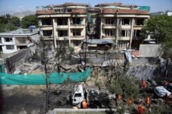 Afghan municipality workers clean a road in front of the damaged buildings, a day after an attack in Kabul, Afghanistan, Thursday, May 9, 2019.