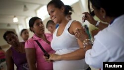 Reaksi seorang ibu hamil saat divaksinasi di sebuah rumah singgah di markas besar Kepolisian Nasional Bolivarian, di daerah kumuh Catia, di Caracas, 29 November 2010.