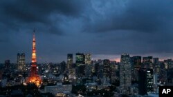 FILE- The Tokyo Tower is lit up at dusk as rain clouds hover over the city's skyline, in Tokyo, Japan, May 29, 2019. The U.N.'s climate chief Patricia Espinosa on Tuesday chided Japan over its new plan to reduce greenhouse gas emissions.