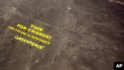 Greenpeace activists stand next to massive letters delivering the message "Time for Change: The Future is Renewable" next to the hummingbird geoglyph in Nazca in Peru, Dec. 8, 2014. 