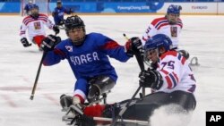 Czech Republic's Jiri Raul keeps the puck from South Korea's Choi Kwang Hyouk, left, during a preliminary Ice Hockey match of the 2018 Winter Paralympics held in Guangneung, South Korea, March 11, 2018.