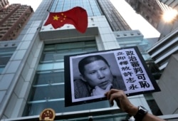 FILE - A placard with a photo of legal scholar Xu Zhiyong is raised by a demonstrator protesting against a Chinese court’s decision to sentence him in prison outside the Chinese liaison office in Hong Kong, Jan. 27, 2014.