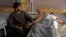 An Afghan wounded man, right, lies on the bed in a hospital as his relative sits on a chair beside him in the city of Kandahar, south of Kabul, Afghanistan, July 9, 2014. 