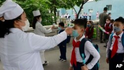 پیانگ یانگ کے ایک سکول میں آنے والے بچوں کا ٹمپریچر چیک کیا جا رہا ہے۔ 25 جولائی 2020