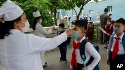 FILE - Kim Song Ju Primary School students have their temperatures checked in Pyongyang, North Korea, June 3, 2020. After months of denying it had any coronavirus infections, North Korea reported its first suspected case July 25, 2020.