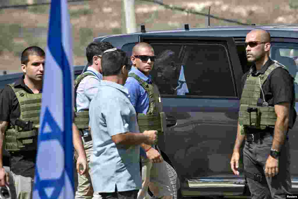 Israeli Prime Minister Benjamin Netanyahu steps out of his car as bodyguards surround him while attending a meeting at an army base near the West Bank city of Nablus, Oct. 6, 2015.