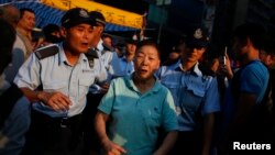 Police escort an anti-Occupy Central supporter to leave an area to prevent a confrontation with pro-democracy protesters inside a tent, which is block a main road at Hong Kong's Mongkok shopping district, Oct. 8, 2014. 