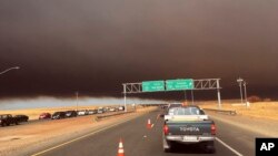 Smoke from the Camp Fire, burning in the Feather River Canyon near Paradise, Calif., darkens the sky as seen from Highway 99 near Marysville, Calif., Nov. 8, 2018. 