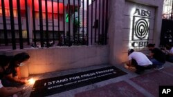 FILE - Employees light candles outside the headquarters of broadcast network ABS-CBN Corp. in Quezon city, Metro Manila, Philippines, May 5, 2020, amid a dispute over its license renewal.