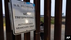 Migrantes esperan entre las vallas fronterizas que separan a Tijuana, México, de San Diego, EEUU, para solicitar asilo a las autoridades estadounidenses, el 12 de abril de 2024, vistos desde San Diego. 