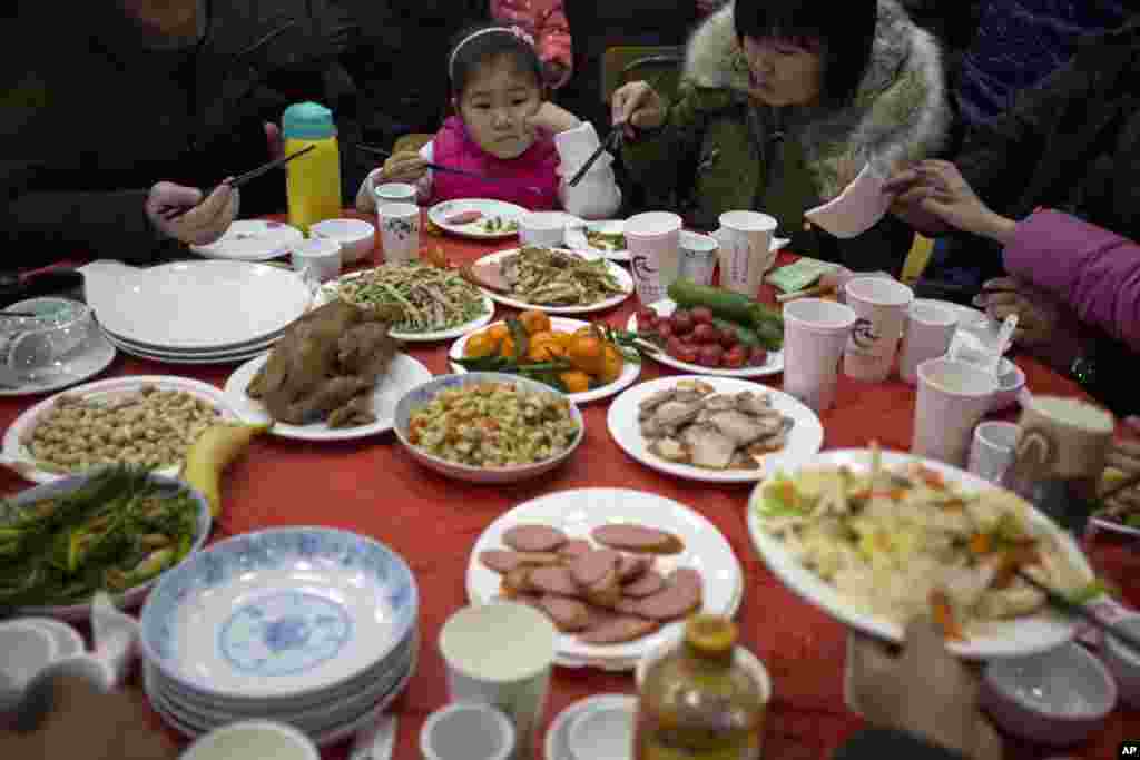 Sebuah keluarga menyantap hidangan dalam &quot;makan malam 1.000 orang&quot; di desa Liuminying, pinggiran kota Beijing (27/1).&nbsp;(AP/Ng Han Guan)