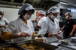 FILE - School canteen workers prepare meals to be distributed to people as part of an emergency plan by the Lisbon city hall to mitigate the social impact of the coronavirus epidemic at the Loios school in Lisbon, April 14, 2020.