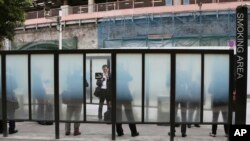 FILE - People are seen gathered at a smoking area in Tokyo, Japan, April 7, 2017. Smoking will be banned at any indoor or outdoor Olympic venue during the 2020 Tokyo games, organizers announced Thursday.
