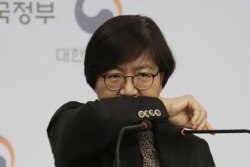 South Korean Centers for Disease Control director Jung Eun-kyeong shows a preferred coughing posture during a press conference at the government complex in Seoul, South Korea, Jan. 23, 2020.