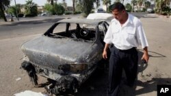 FILE - An Iraqi traffic policeman inspecting a car destroyed by a Blackwater security detail in al-Nisoor Square in Baghdad, Iraq, Sept. 25, 2007. 