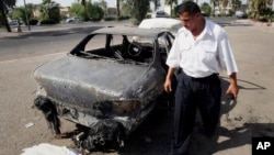 FILE - An Iraqi traffic policeman inspecting a car destroyed by a Blackwater security detail in al-Nisoor Square in Baghdad, Iraq, Sept. 25, 2007. 