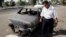 FILE - An Iraqi traffic policeman inspecting a car destroyed by a Blackwater security detail in al-Nisoor Square in Baghdad, Iraq, Sept. 25, 2007. 