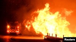 Los bomberos combaten un incendio, mientras un incendio forestal impulsado por el viento continúa ardiendo en Canyon Country, al norte de Los Ángeles, California, EE.UU., el viernes.