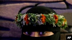 A Saudi woman poses for a picture wearing a colorful crown that is native to the the village of Rijal Almaa, during the al-Soudah festival, in Abha, southwest Saudi Arabia, Aug. 23, 2019.