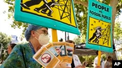 FILE - Climate activists demonstrate outside a hearing of the California Air Resources Board in Sacramento, Calif., June 23, 2022. A new law requires California to remove as much carbon from the air as it emits by 2045..