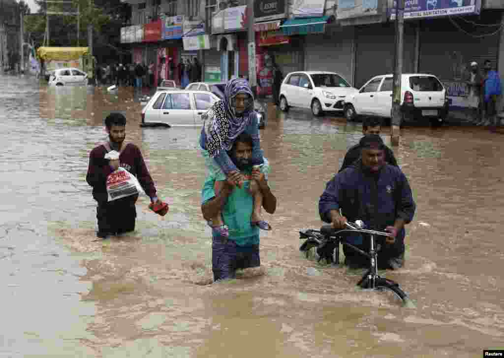 A Kashmiri man evacuates an elderly woman to a higher ground at a flooded road in Srinagar, India, Sept. 7, 2014.