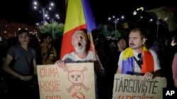 Protesters shout anti-government slogans holding a banner that reads "PSD (Social Democratic Party) - The red plague" outside the government headquarters in Bucharest, Romania, Sunday, Aug. 27, 2017. 