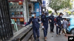 Members of Yangon City and Development Committee spray disinfectant along a sidewalk in hopes of curbing the spread of the new coronavirus, Myanmar, March 29, 2020. 