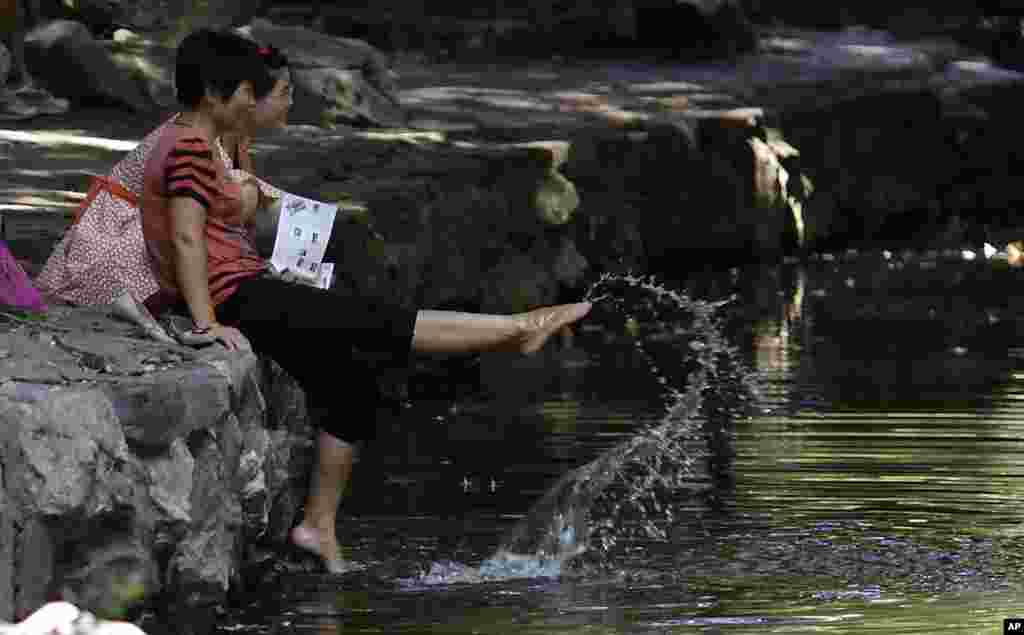 Seorang perempuan mendinginkan diri dari panas terik matahari di sebuah taman di Shanghai, Cina.