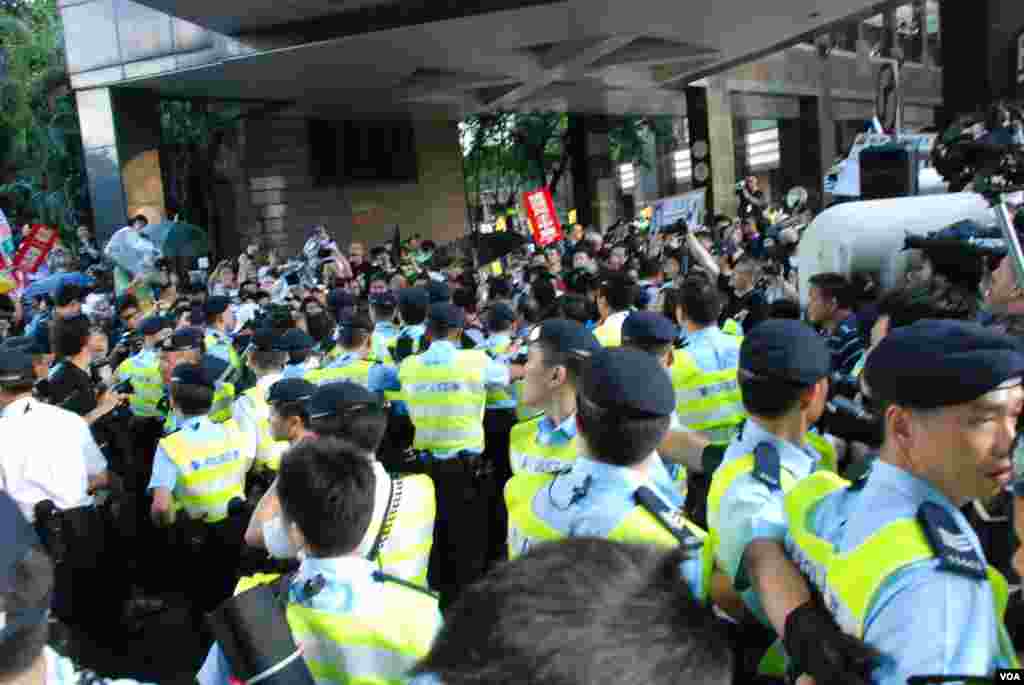 香港警方發射胡椒噴霧阻止示威者衝擊鐵馬，有示威者開雨傘遮擋