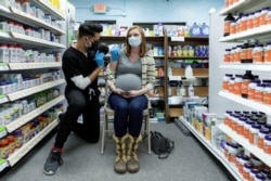 FILE - Michelle Melton, who is 35 weeks pregnant, receives the Pfizer-BioNTech vaccine against COVID-19 at Skippack Pharmacy in Schwenksville, Pa., Feb. 11, 2021.