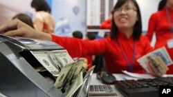 A Vietinbank employee counts US dollars at a currency exchange counter at the National Convention Center, the venue for the 44th annual meeting of Asian Development Bank (ADB), in Hanoi, May 5, 2011.