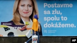 A man walks past a campaign poster for Zuzana Caputova in Bratislava, Slovakia, Friday, March 15, 2019. Caputova is one of the favorite candidates to succeed Slovakia's President Andrej Kiska in the upcoming election. 