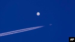 Sebuiah jet tempur terbang melintasi balon yang berada di atas Samudra Atlantik, di lepas pantai South Carolina, pada 4 Februari 2023. (Foto: Chad Fish via AP)