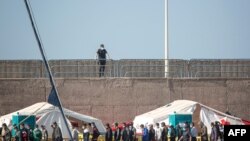 Migrants from a group of 1,334 rescued from different boats remain in the port of Arguineguin while being cared for by the Spanish Red Cross and the National Police on the Spanish Canary island of Gran Canaria, Nov. 20, 2020. 